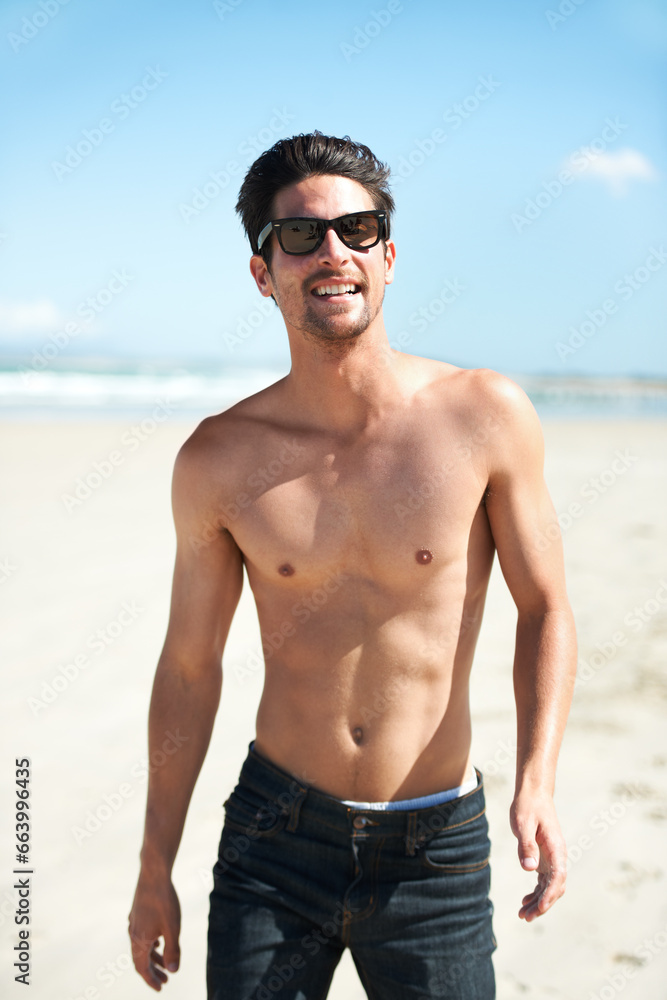 Obraz premium Summer, sunglasses and the body of a man on the beach for travel, freedom or adventure on vacation. Nature, sand and a young person shirtless by the ocean or sea on a tropical coast for holiday