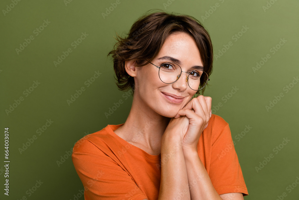 Portrait of young nice girlfriend holding hands together wearing orange t shirt touch cheek dreams isolated on khaki color background Portrait of young nice girlfriend holding hands together wearing orange t shirt touch cheek dreams isolated on khaki color background