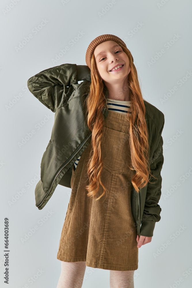 child fashion, cheerful girl with long hair and knitted hat standing in dress and winter jacket child fashion, cheerful girl with long hair and knitted hat standing in dress and winter jacket