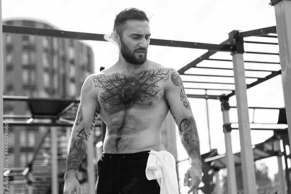 Muscular bodybuilder handsome man with naked torso trains triceps in a