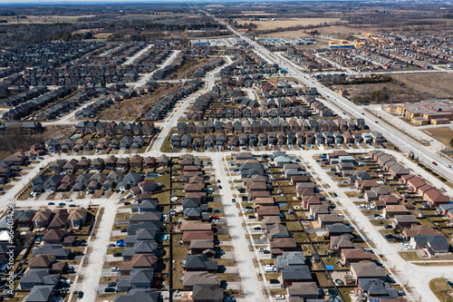 Aerial view of Barrie, Ontario, highlighting dense residential areas adjacent to the expansive, icy expanse of Lake Simcoe. The urban landscape showcases modern homes and infrastructure against a sere