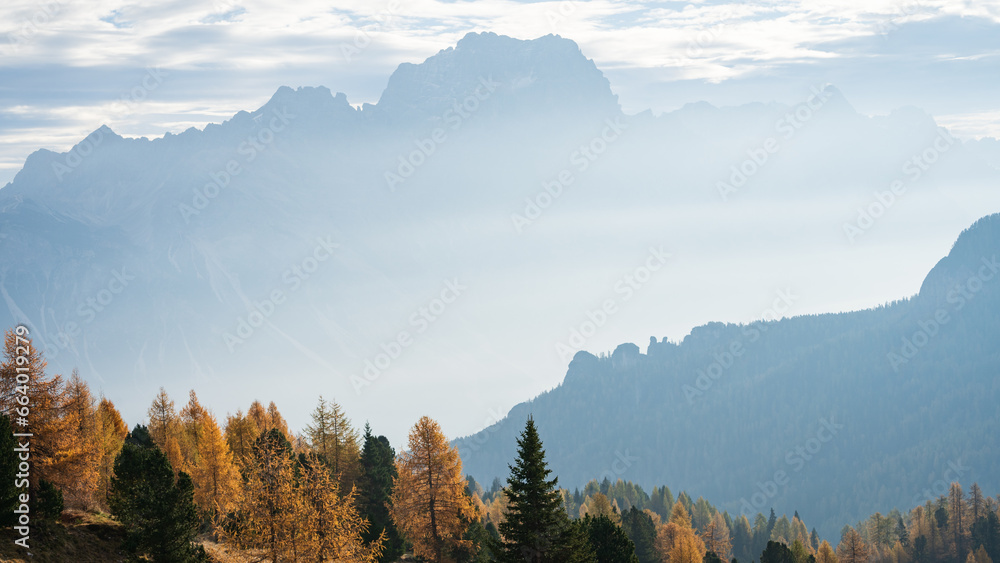 Colorful autumn alpine landscape with hazy mountains and golden larches, Italy, Europe