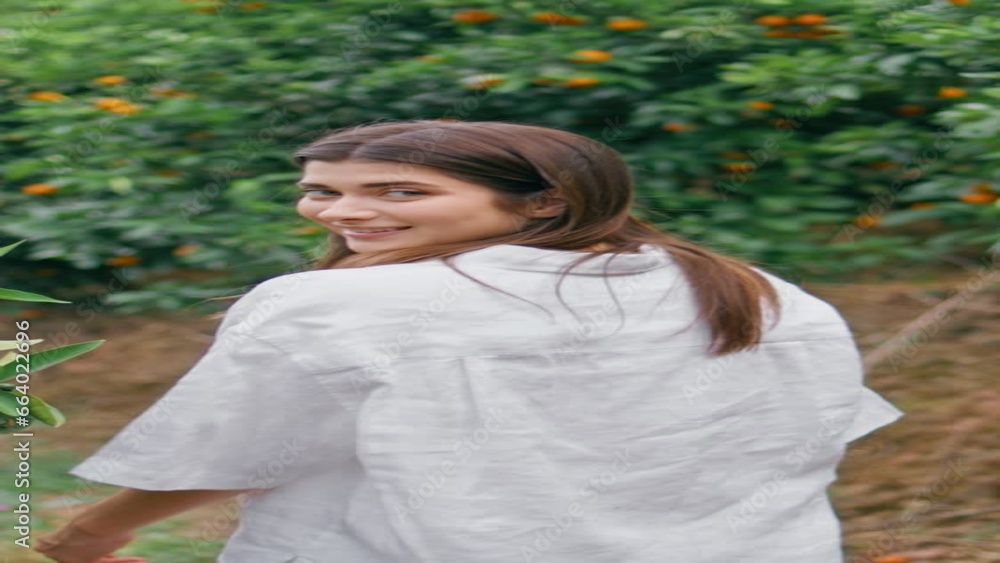 Relaxed girl walking orange plantation vertical back view. Lady turn to camera Relaxed girl walking orange plantation vertical back view. Lady turn to camera