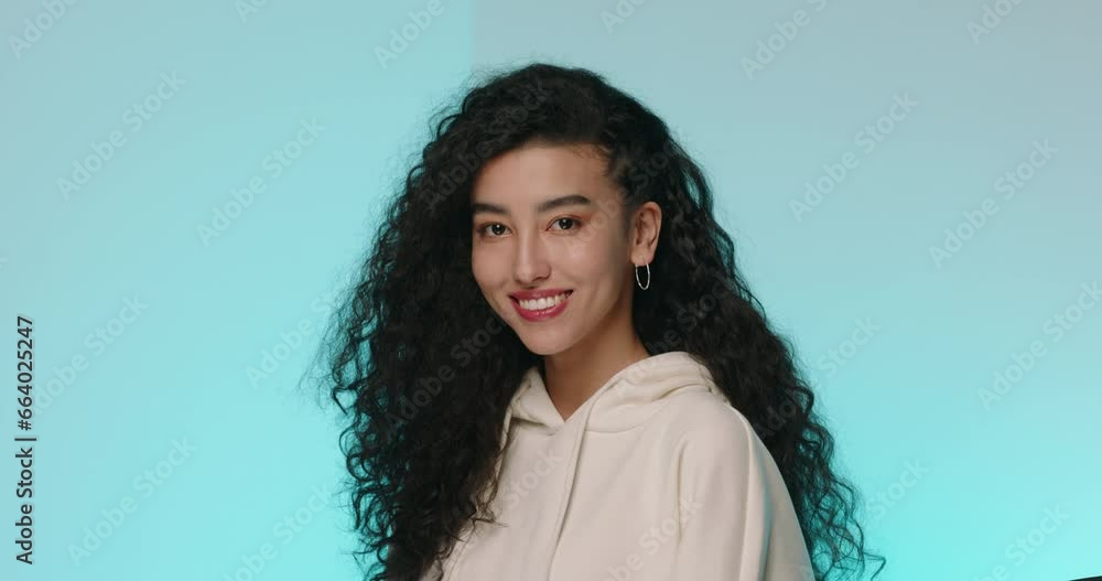 Portrait of young beautiful confident woman. Girl with Asian appearance and curly hair poses. Professional photo shoot. Beautiful female model posing at studio. Modern people, young adult and youth Portrait of young beautiful confident woman. Girl with Asian appearance and curly hair poses. Professional photo shoot. Beautiful female model posing at studio. Modern people, young adult and youth
