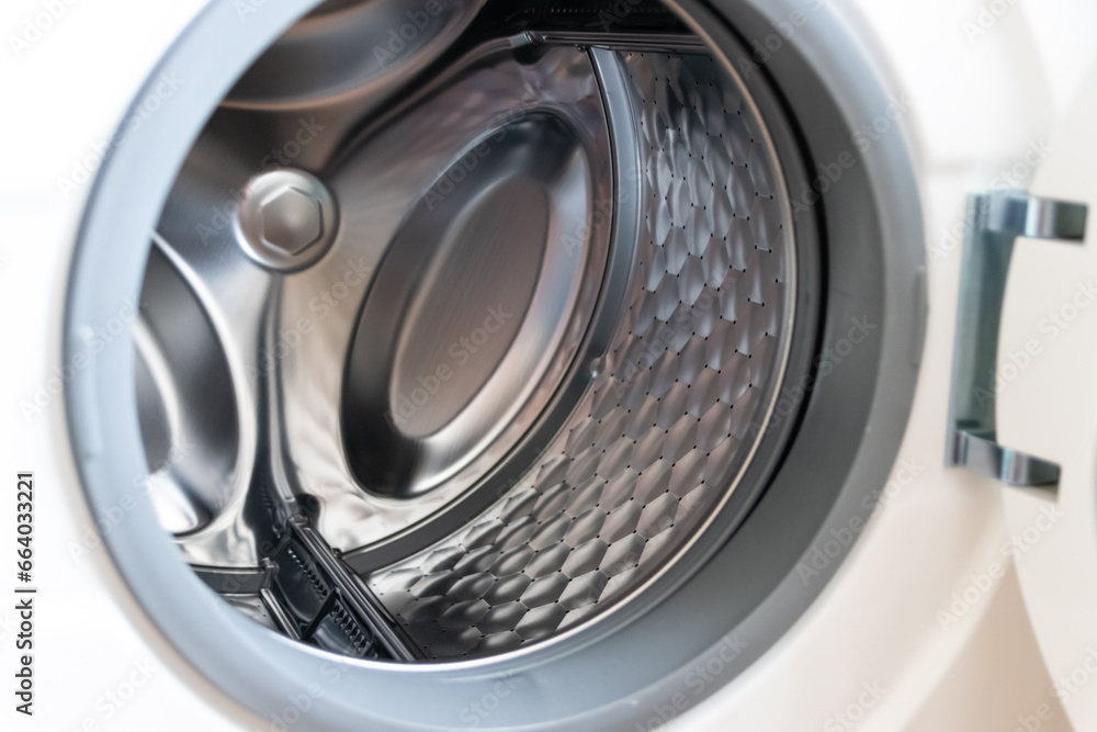 View into washing machine drum inside with stainless steel drum interior shows household equipment for cleaning clothes with dry cleaner and front loader for easy housework laundromat machine empty View into washing machine drum inside with stainless steel drum interior shows household equipment for cleaning clothes with dry cleaner and front loader for easy housework laundromat machine empty