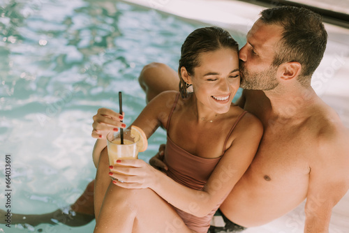 Obraz na plátne Young couple relaxing by the indoor swimming pool