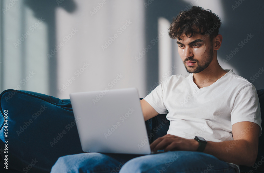 Freelancer man using laptop computer at home, typing on keyboard. Working remotely on online project.