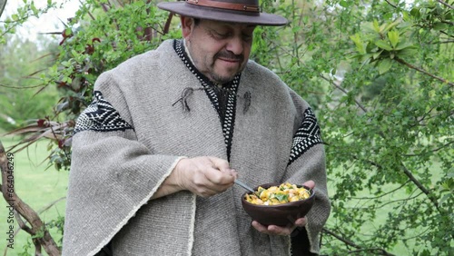 Front view of country mapuche man, eating and tasting diguenes, cyttaria espinosae, edible mushroom in the countryside photo