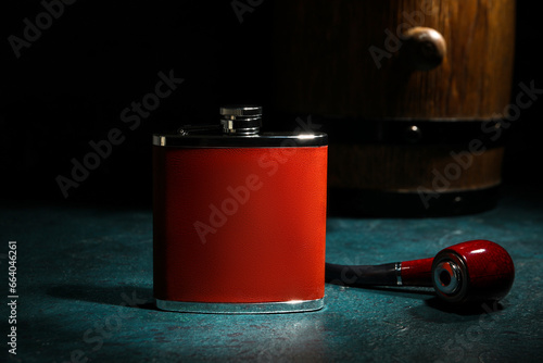 New hip flask and smoking pipe on dark background