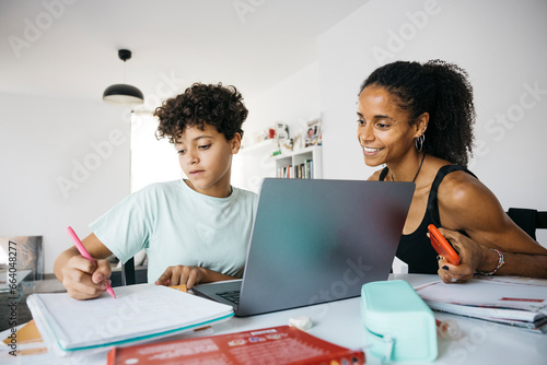 Tableau sur toile Cheerful woman helping her smiling daughter doing homework