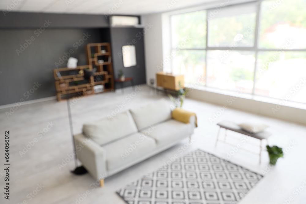 Blurred view of modern living room with sofa and soft bench