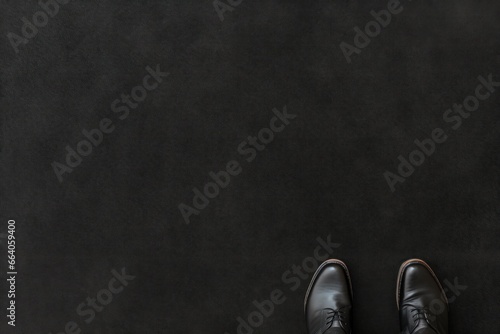 male feet in shoes stand on a black carpet, top view. copy space