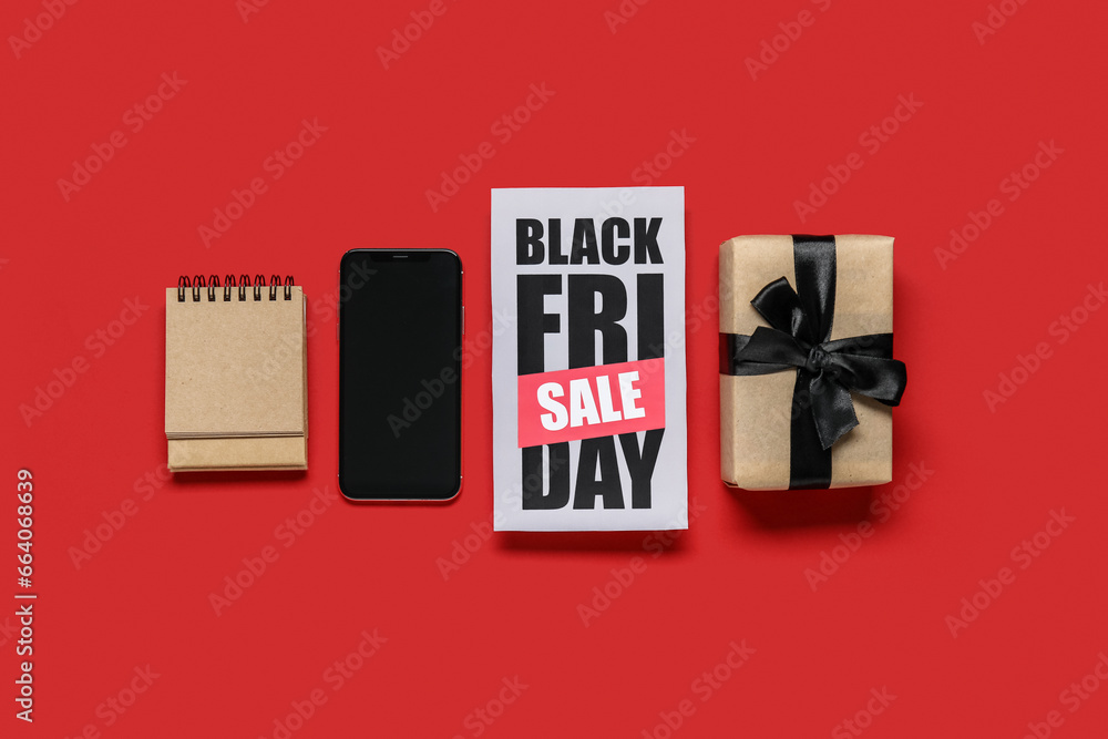 Black Friday sale greeting card with mobile phone, notepad and gift box on red background Black Friday sale greeting card with mobile phone, notepad and gift box on red background