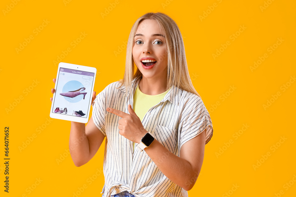 Beautiful young woman with tablet shopping online on yellow background Beautiful young woman with tablet shopping online on yellow background