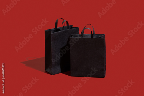Black paper shopping bags on red background. Black friday sale, shopping concept