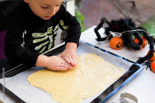 boy dressed as a skeleton preparing halloween cookies.Happy boy preparing for halloween. Festival in the kitchen.