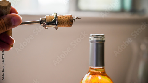 Hand holding wine opener with bottle in background and copy space available photo