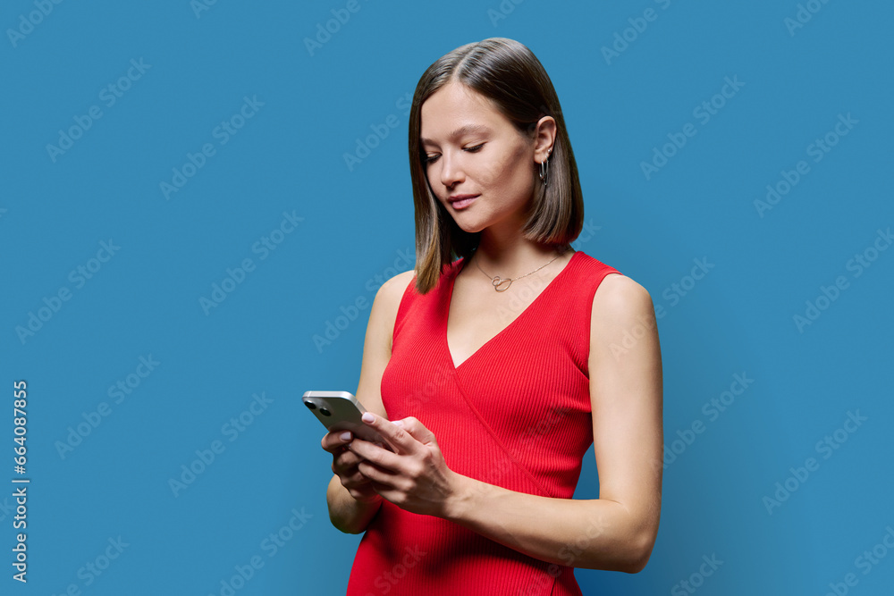 Young woman with smartphone in hands on blue studio background Young woman with smartphone in hands on blue studio background