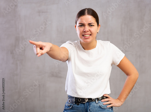 Photos Photo of aggressive young woman banishing crossly standing against light unicolo