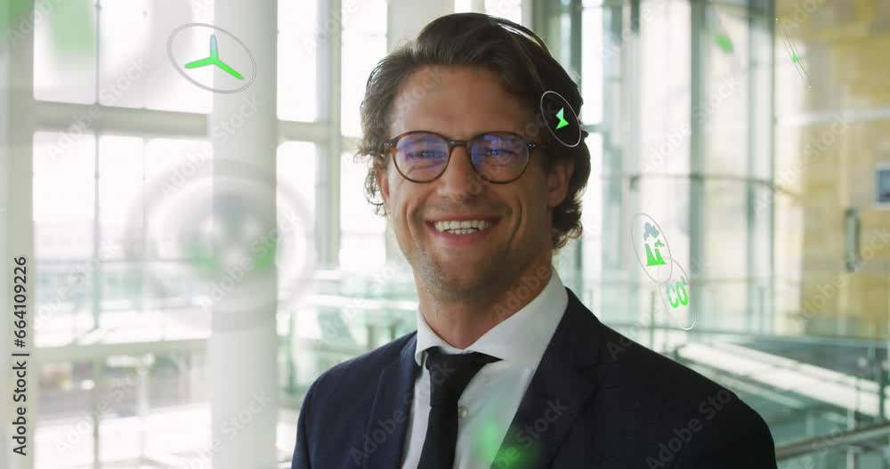 Animation of eco icons over smiling caucasian businessman in office Animation of eco icons over smiling caucasian businessman in office