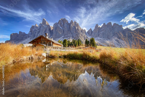 Obraz na płótnie Scenic view of Geisler Alm Rifugio delle Odle in front of dolomites mountains and reflection in the water of a pond, South Tyrol, Italy w salonie