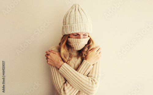 Fototapeta Woman freezing trying to warm up wearing warm soft knitted clothes, winter hat a