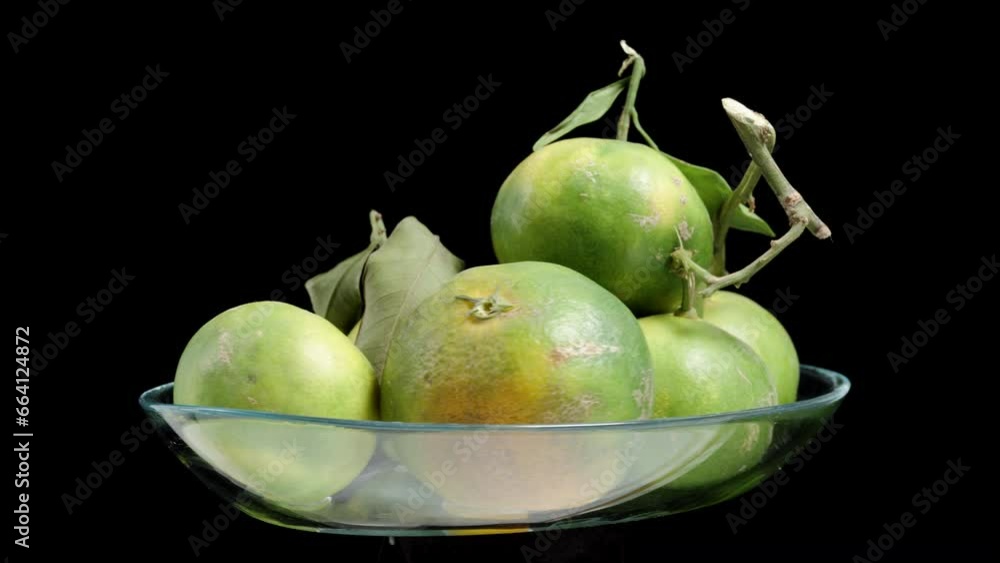 Green Tangerine in a glass bowl. They rotate on a black background, looped video, isolated. Green Tangerine in a glass bowl. They rotate on a black background, looped video, isolated.