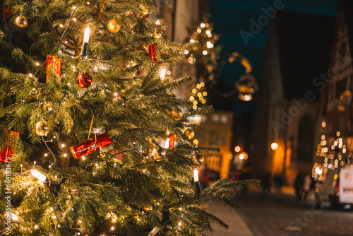  Christmas tree with gifts, garlands and people walking out of focus.Christmas old town in the evening in Europe.Festive street decorations in European cities
