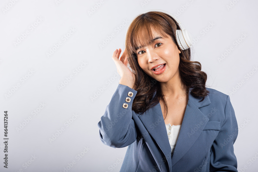 Excited woman in Bluetooth headphones smiles, immersed in music from her phone's radio. Studio shot, isolated on white. This happy Asian young female embraces modern technology for her enjoyment. Excited woman in Bluetooth headphones smiles, immersed in music from her phone's radio. Studio shot, isolated on white. This happy Asian young female embraces modern technology for her enjoyment.