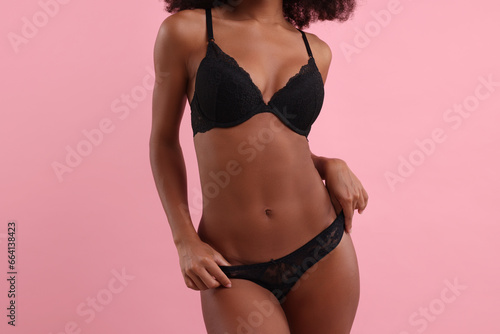 Woman in elegant black underwear on pink background, closeup