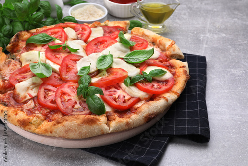 Delicious Caprese pizza with tomatoes, mozzarella and basil served on light grey table, closeup