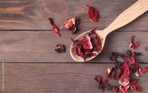Spoon with dry hibiscus tea on wooden table, flat lay. Space for text