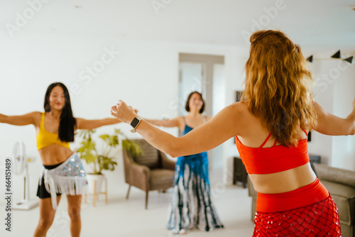 Picture of a group of female friends performing Belly Dance in beautiful costumes. with fun at their homes, woman dance, Belly dancer in legging and hip scarf dancing.