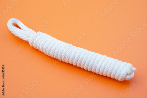 White rope  Keeping long rope to be shorter on orange background. Concept  practice to tie different pattern of rope to apply in daily life such as tying things or doing  activities.       