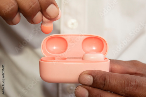 Close-up of a male hand holding a wireless buds in a pink case