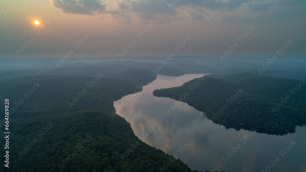 An aerial view of Esson Lake reflecting the sky on a hazy day in the summer during sunset An aerial view of Esson Lake reflecting the sky on a hazy day in the summer during sunset