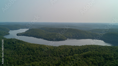 An aerial view of Esson Lake reflecting the sky on a hazy day in the summer during sunset