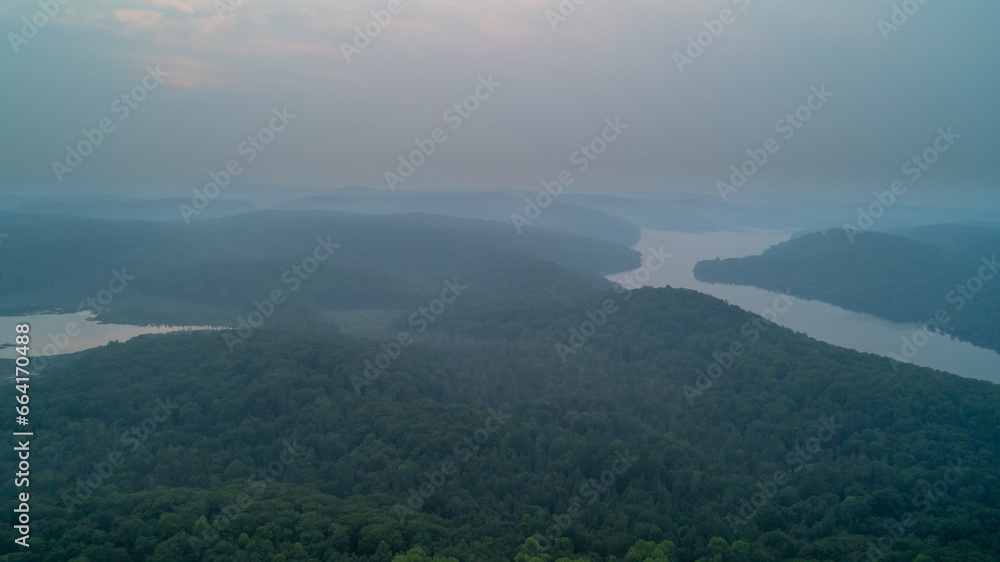 An aerial view of a forest, marsh and lake on a hazy day due to wildfires
