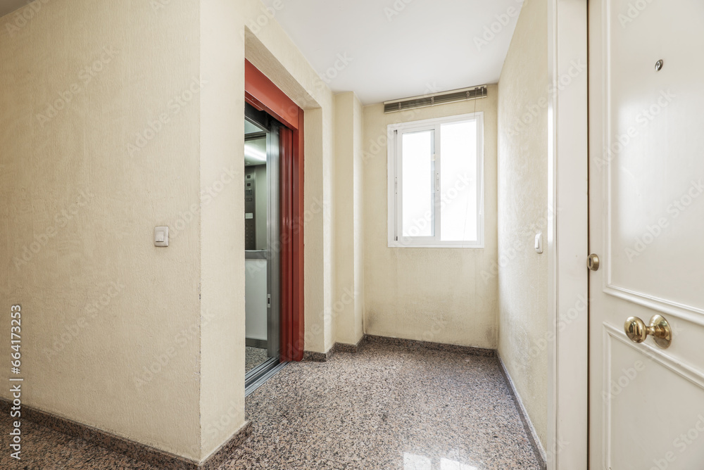 Stair landing of an urban residential apartment building with shiny granite floors and an elevator with a metal sliding door Stair landing of an urban residential apartment building with shiny granite floors and an elevator with a metal sliding door