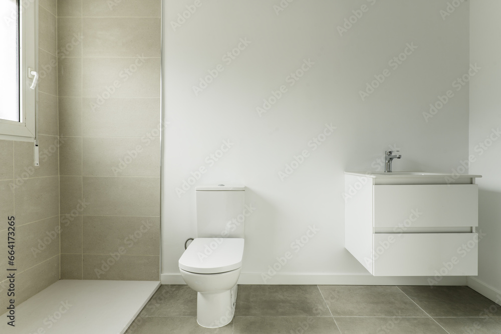 Bathroom of a home with two-tone white and gray tiles and white porcelain sink on white lacquered wooden furniture with two drawers hanging on the wall Bathroom of a home with two-tone white and gray tiles and white porcelain sink on white lacquered wooden furniture with two drawers hanging on the wall