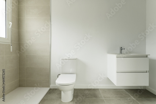 Bathroom of a home with two-tone white and gray tiles and white porcelain sink on white lacquered wooden furniture with two drawers hanging on the wall
