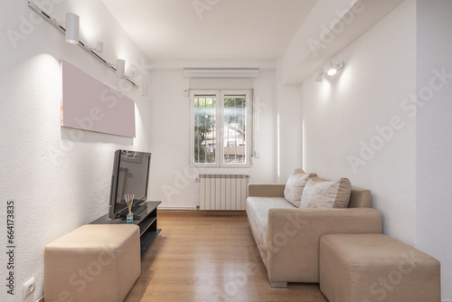 Sparsely furnished apartment with sofas that need to be upholstered next to a barred window