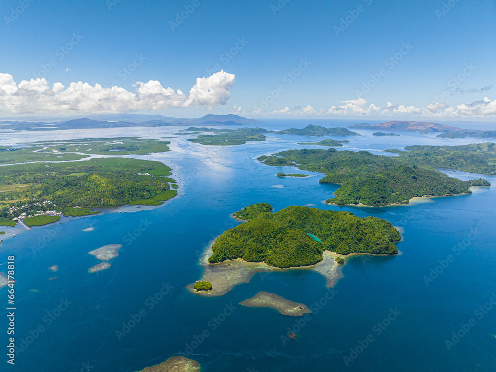 Air survey of tropical islands and azure water and blue sky and clouds. Tinago Island. Mindanao, Philippines.