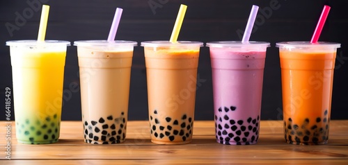 Plastic cups of different tasty bubble tea on wooden background. © Anny