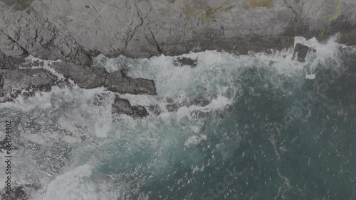 Plano aéreo zenital desde drone de mar picado con olas con mucho viento chocando contra rocas en la costa. d-log 60fps. photo