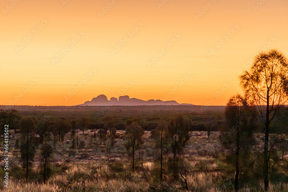 Sunset over australian outback in Northern Territory Australia, with Mount Olgas at background.