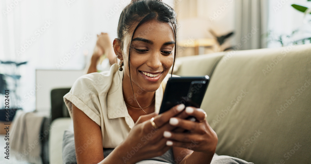 Phone, smile and woman on sofa typing in home, social media and reading email notification to relax. Smartphone, happy and Indian person in living room on mobile app, scroll website and communication Phone, smile and woman on sofa typing in home, social media and reading email notification to relax. Smartphone, happy and Indian person in living room on mobile app, scroll website and communication