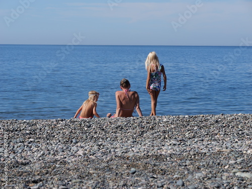 mom sits on the beach with her two daughters