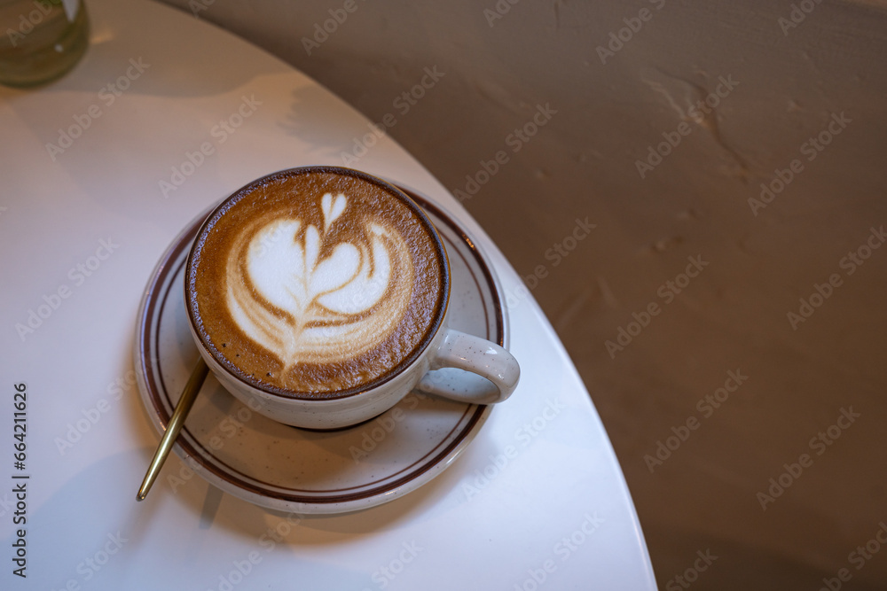 Hot coffee latte with latte art milk foam in cup mug on wood desk on top view. As breakfast In a coffee shop at the cafe,during business work concept,vintage style Hot coffee latte with latte art milk foam in cup mug on wood desk on top view. As breakfast In a coffee shop at the cafe,during business work concept,vintage style