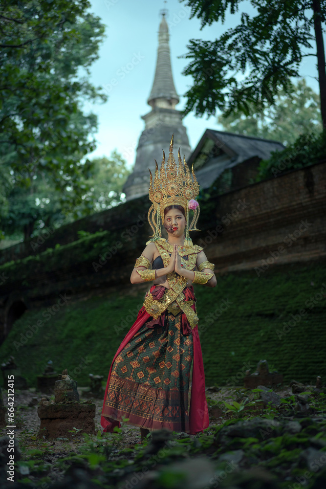 Pretty Asian woman wearing an ancient Traditional Khmer Cambodian Apsara dress costume shows the ghost a typical fairy Apsara.